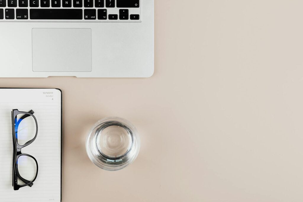 How Can I Manage ADHD-Related Executive Dysfunction in Daily Life? 1 Overhead view of a clean workspace with a laptop, notebook, eyeglasses, and a glass of water.