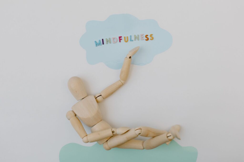 Wooden mannequin depicting mindfulness concept against pastel background.