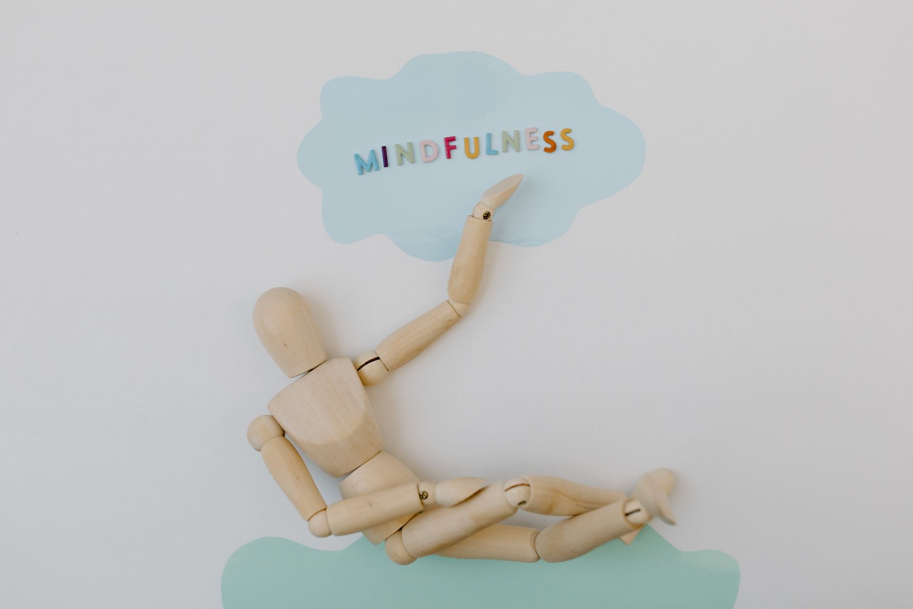 Wooden mannequin depicting mindfulness concept against pastel background.