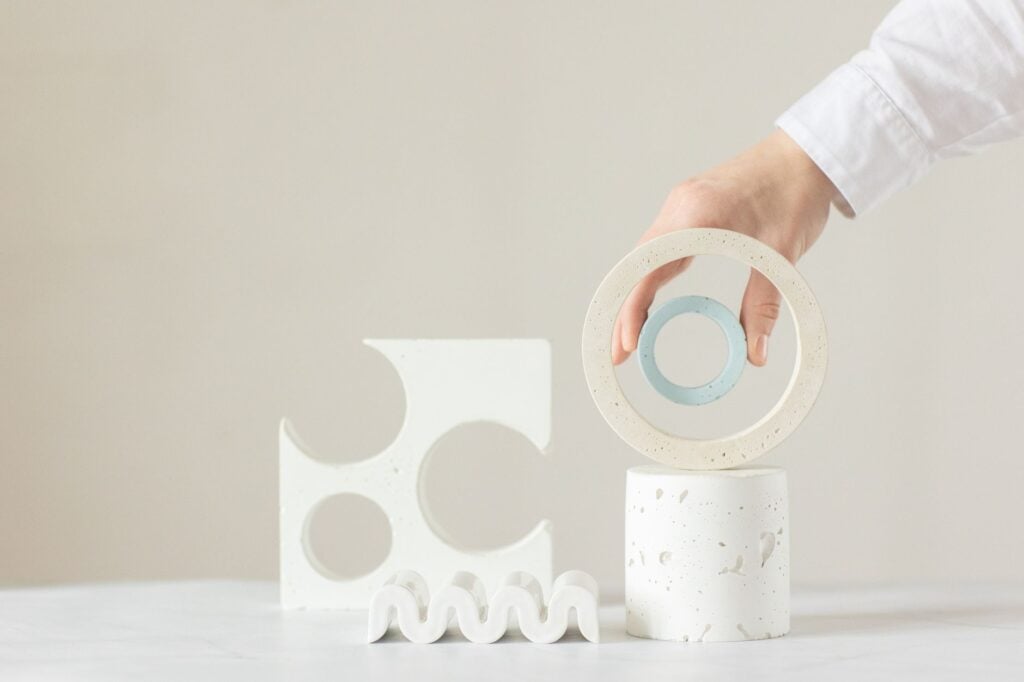 How Can I Manage Bipolar Disorder-Related Cognitive Challenges in Daily Life? 2 A hand arranging minimalist geometric shapes in a bright indoor setting.