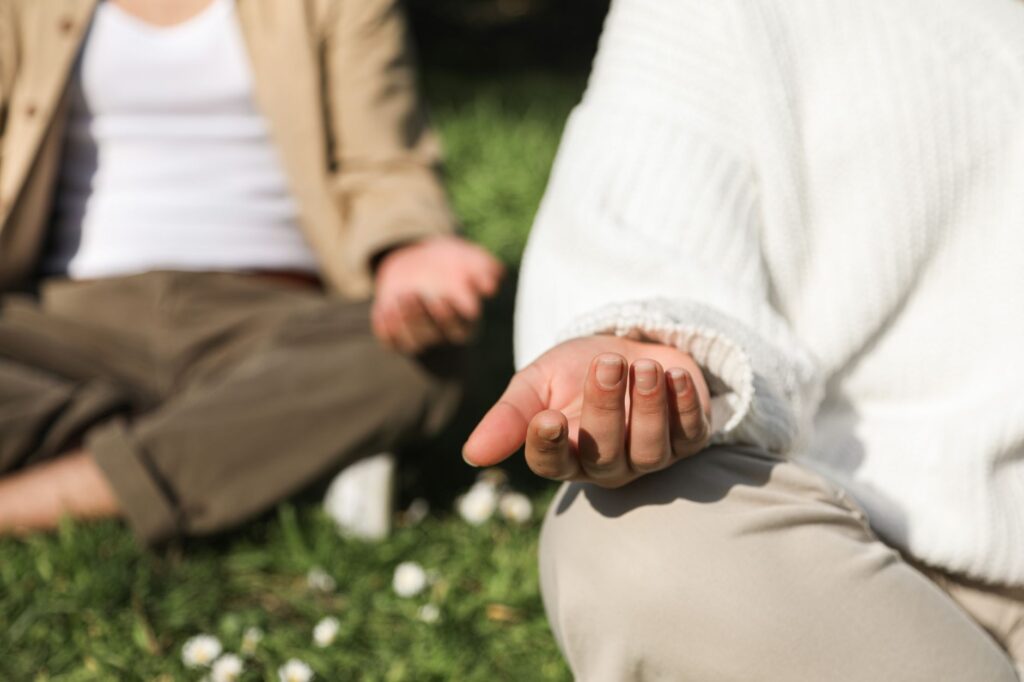 How Can I Manage Anxiety-Related Sleep Disturbances to Improve Restful Nights? 2 Two people meditating outdoors, focusing on hands in a peaceful setting.